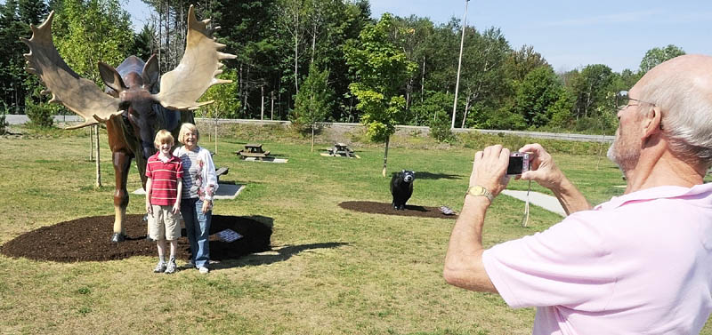 Benjamin Hagle, of Bar Harbor, left, and Nancy Ottman, of St. Paul, Minn., pose in front a fiberglass moose as Jim Hagle, of Nashville, Tenn. snaps their picture on Thursday morning at the West Gardiner Service Plaza on Route 126 that serves both Interstate 95 and the Maine Turnpike.