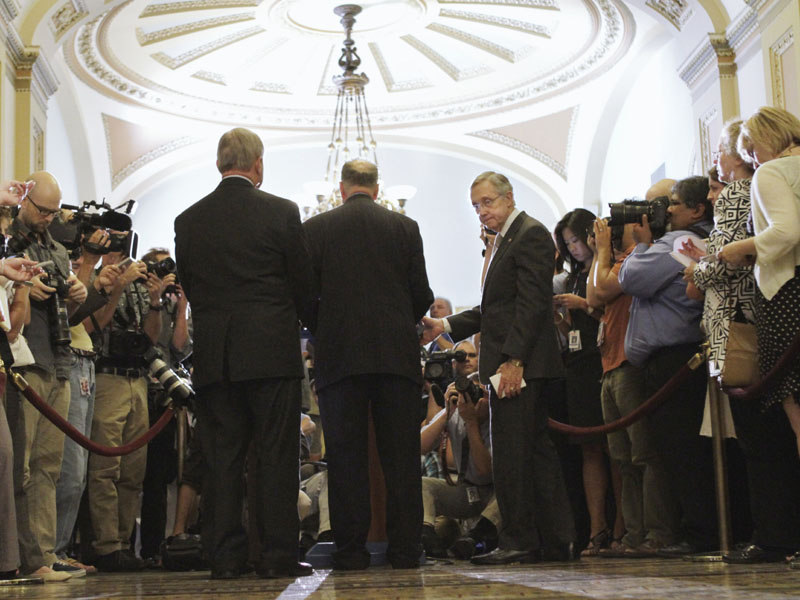 MEET THE PRESS: Senate Majority Leader Harry Reid of Nev., center right, turns away from the microphones during a news conference Tuesday on Capitol Hill after final passage of the emergency legislation to prevent a default on government debt obligations.