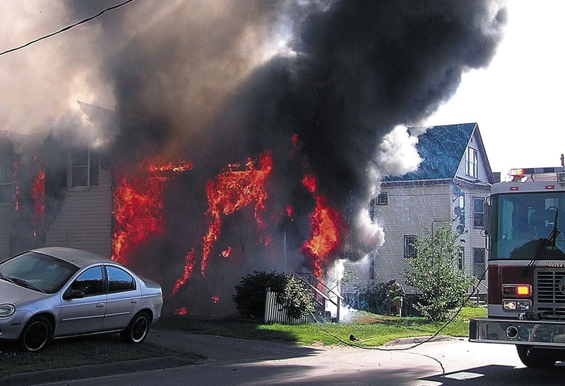 ON FIRE: A house on Oak Street in Waterville is consumed by flames Tuesday morning as firefighters arrive on scene.