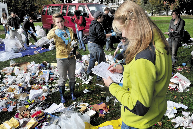 YUCK: University of Maine in Farmington student Cathryn Cunningham, left, shows types and brands of waste products to Mel Christensen, foreground, who categorized the trash during an archaeology class on campus Wednesday to document material discarded during a 24-hour period.