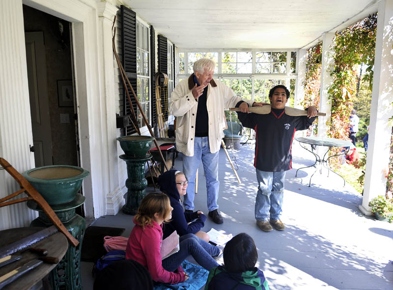 YOKE'S ON HIM: Gerry Mahoney, left, helps Hall-Dale sixth grader Jordan Perry put an 18th century bucket yoke over his shoulders Thursday on the porch of the Vaughan Homestead in Hallowell. Students and parents from the Hall-Dale sixth grade participated in the annual tour at the Homestead that was built in 1794 and has been in the same family for over 200 years. Children learned about the biology, geology and forestry of Vaughan Woods from community experts as well as the history from Mahoney. The yoke was used to water buckets, Mahoney said.