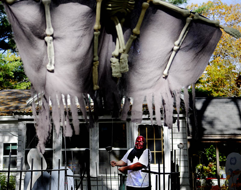 LET YOUR FREAK FLAG FLY: Donald Hallett hangs a Halloween decoration Tuesday outside his Manchester home. Hallett goes all out setting up his home for the holiday. “We like to have a little bit of fun,” he said.