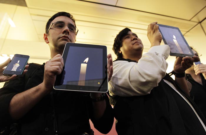 Apple computer fans at an Apple Store in the Ginza shopping district in Tokyo hold their iPhones and iPads during a vigil to pay tribute to Steve Jobs.