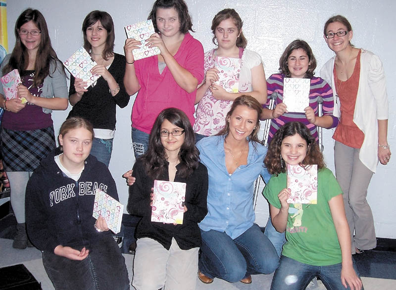 Students at Mt. Blue Middle School in Farmington show off their new journals that Ashley Underwood, 26, of Benton, gave them Tuesday morning. From left in back row are Emily McCarthy, Shamira Tanguay, Destiny Burnell, Miranda Chapman, Jazmine Gorman and art teacher Danielle Guerrette. In front from left are Mikayla Reynolds, Emily Nicholoff, Underwood and Brittany Meryhew.