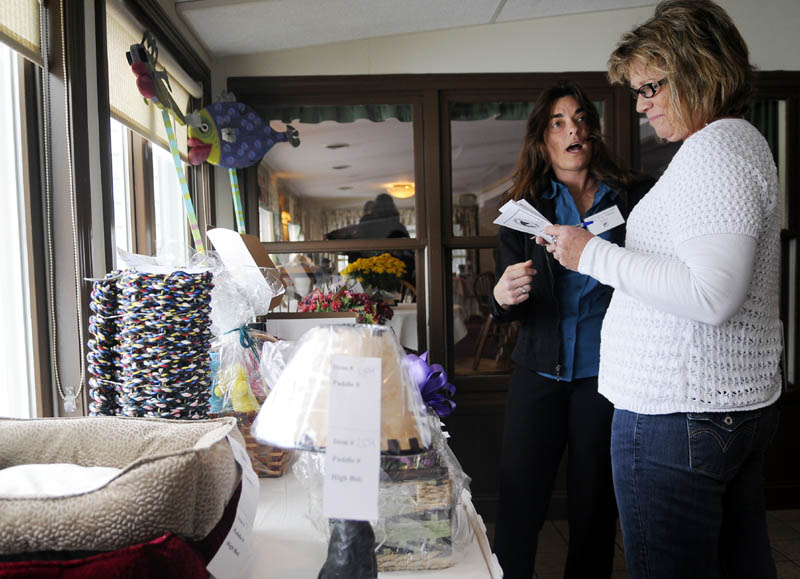 Mary Kay Adams, left, chats Sunday with Kim Nixon while evaluating donated items up for sale at the Kibbles 'N Bids Auction in Manchester. The 13th annual auction, sponsored by Charlies' Super Motor Mall, raised funds for the Kennebec Valley Humane Society.