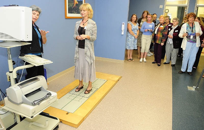 Physical therapist Laurie LaBonte, left, tells Donna Boutin, center, about the Balance Master device in the large gym at the new MaineGeneral Musculoskeletal Center located at 15 Enterprise Drive on Wednesday night in Augusta. It is used to help with lower extremity rehab and the screen shows how much of their weight the person standing on it has on each leg.