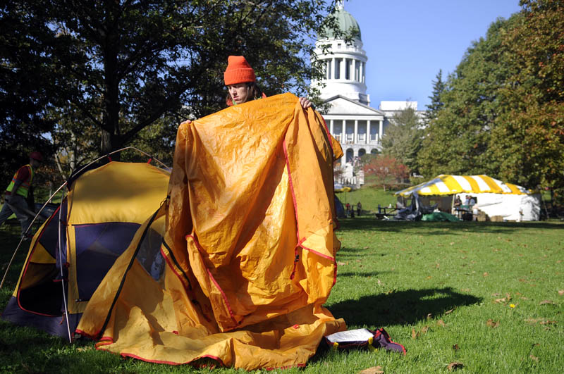 Daphne Loring shakes dew off a tarp Monday morning while breaking down her tent in Capitol Park. The Greene farmer spent two nights in the park as part of the Occupy Augusta protest. Loring said she needed to tend to the hogs she is raising but plans to return to the camp site.
