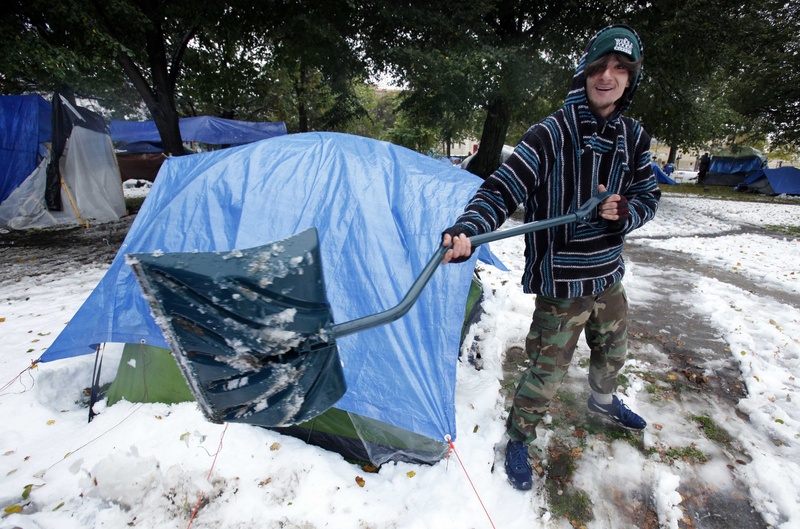 Blake Smith shovels snow in front of a tent at an Occupy Maine camp in Portland's Lincoln Park today.