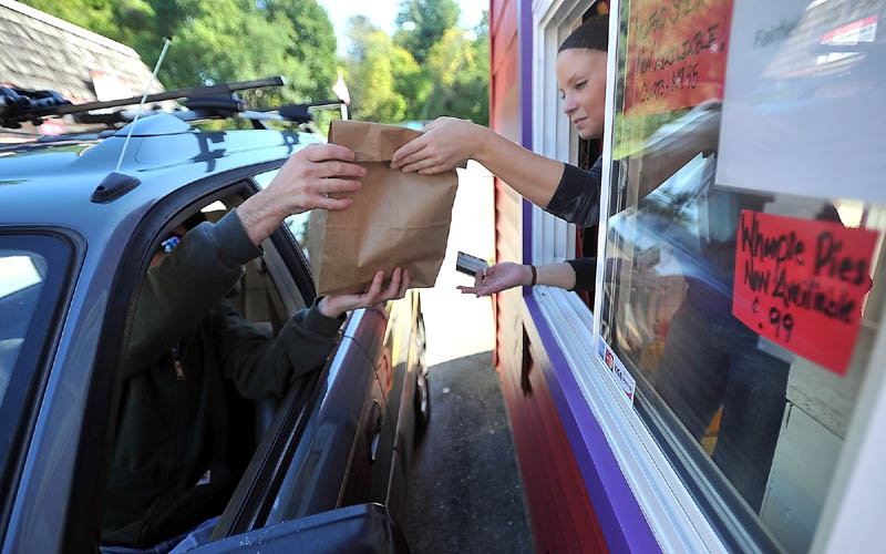 FAST FOOD: Danny McKinnis, left, picks up his order from Erin Falconer, right, at The Red Barn drive-through window Thursday afternoon in Winslow.