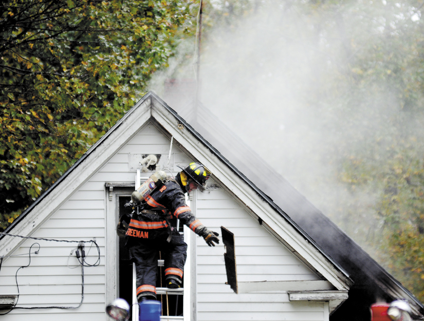 A firefighter removes a smoldering clapboard Sunday from a Richmond house that caught fire. A boy inside the home was hurt in the blaze, according to officials. The fire was reported around 10:30 a.m. and heavily damaged the home on River Road.