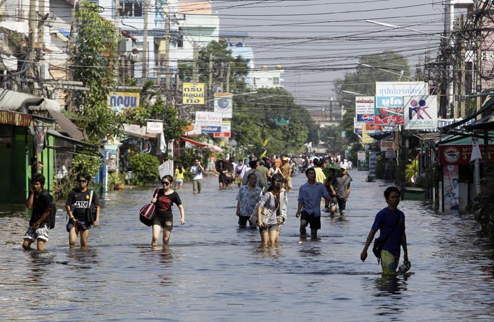 Thai people wade through a flooded area in Phatum Thani Province, north of Bangkok today. Thai authorities were staging a fighting retreat today against floodwaters that threaten Bangkok, after the country's oldest factory park was completely inundated and a nearby one faced imminent threat.