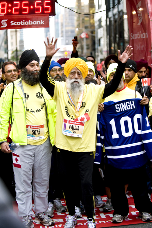 In this photo provided by Scotiabank Toronto Waterfront Marathon, Fauja Singh, 100, celebrates at the finish line after completing the Toronto Waterfront Marathon on Oct. 16.