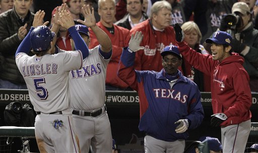 Texas Rangers' Ian Kinsler is congratulated in the dugout after scoring on a sacrifice fly ball during the ninth inning of Game 2 of baseball's World Series against the St. Louis Cardinals on Thursday in St. Louis.
