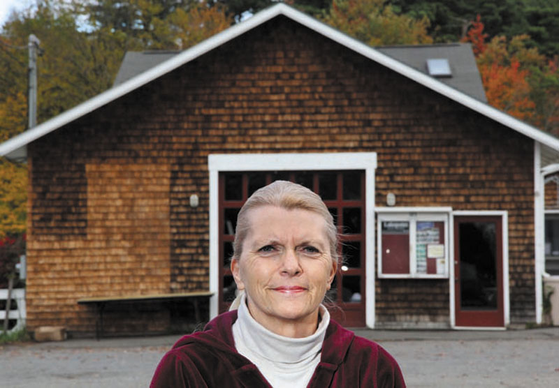 Jan Partridge, owner of Balloons & Things in Belgrade Lakes, has collected a petition with signatures from more than 100 people wanting to save the old marina (background) across from her store on Main Street.