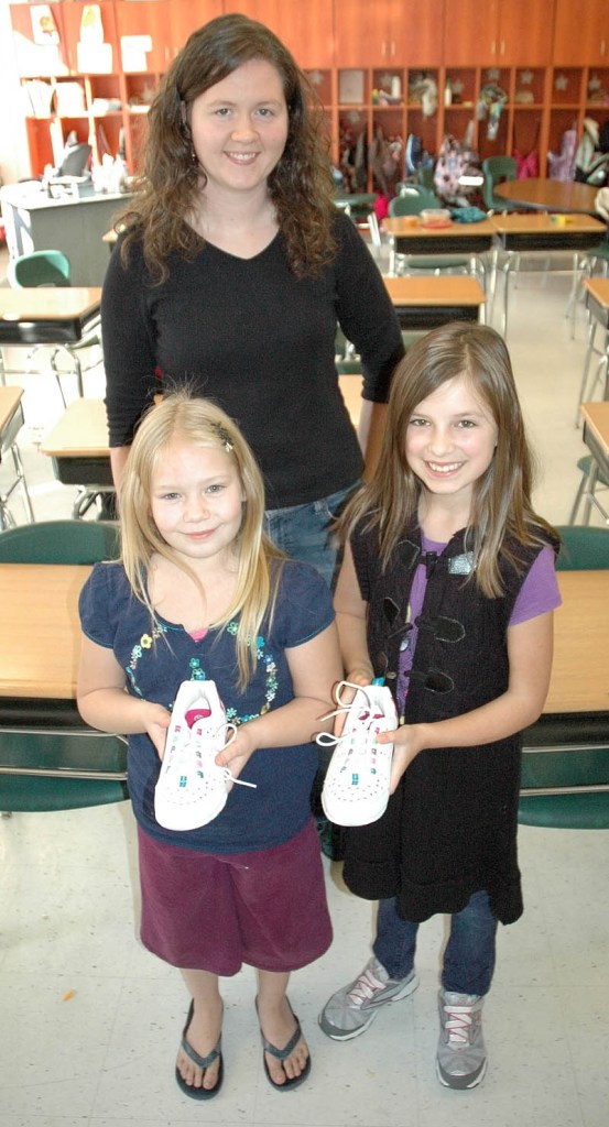 CHRISTMAS SHOES: Fourth grade teacher Amanda Pingree stands in her classroom with two of her students, Jenna Oliver, 9, of North Anson, and Annika Carey, 10, of Embden. The Carrabec Community School class is starting a cross-cultural exchange program with students in Cameroon and is currently collecting nice children’s shoes to send over for Christmas.