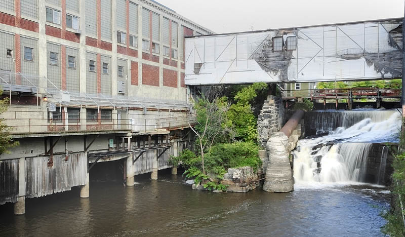 A waterfall that used to be used for hydropower runs past the Bates Mill No. 5 in Lewiston, the proposed site of a casino.