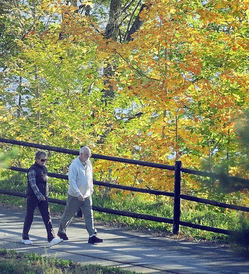 People walk along the Kennebec River Rail Trail on a sunny Saturday morning in Augusta.