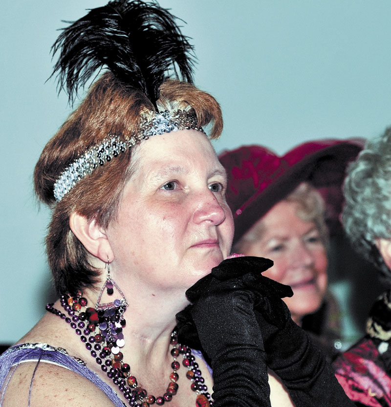 A SPOT OF TEA: Diane Louten, left, dressed as a flapper and Shirley Chaffee wore a signature hat as the Red Hat Society and others listen to quilter Debbie Quirion during the REM Vintage Tea social Sunday at the Center in Waterville. Dozens dined on gourmet hors d’oeuvres and desserts.