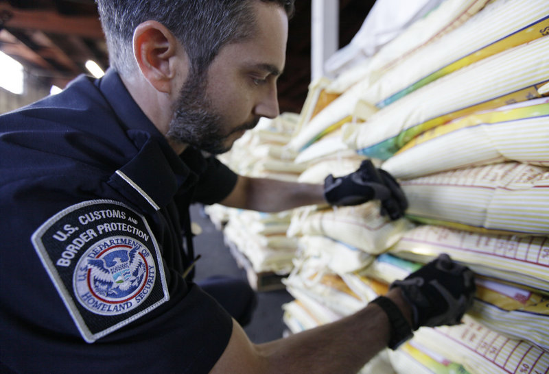 INSPECTION: Agriculture specialist Mark Murphy with U.S. Customs and Border Protection examines bags of rice during an inspection Aug. 23 in Oakland, Calif. Dozens of foreign insects and plant diseases slipped undetected into the U.S. after 9/11.