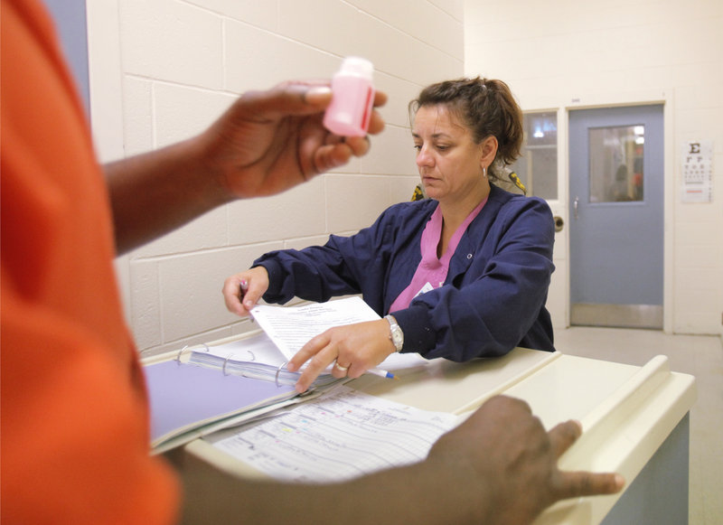 2014 FILE PHOTO: Carmen Mulholland, a nurse with Allied Resources, dispenses methadone to an inmate at the Penobscot County Jail in Bangor last month. Most of the 6,000 inmates who come through the jail in a year are taking some sort of medication, often for opiate addiction.