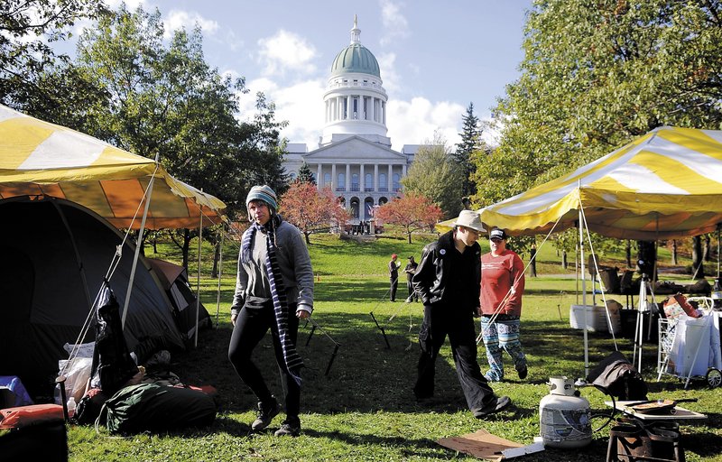 Protesters walk Sunday between canopies that cover tents on Capitol Park in Augusta. People affiliated with Occupy Augusta spent the night in the Park and said they will stay indefinitely.