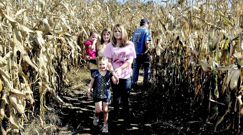 A MAIZING: Groups of kids and adults pass each other while negotiating the 13-acre corn maize at the Sandy River farm on Route 2 in Farmington on Sunday. The maize and other attractions created by farmer Herbert "Bussie" York is open on weekends through Oct. 30. In front is Destiny Anderson along with Tori Wright followed by Danielle Anderson carrying Jasmine Penney.