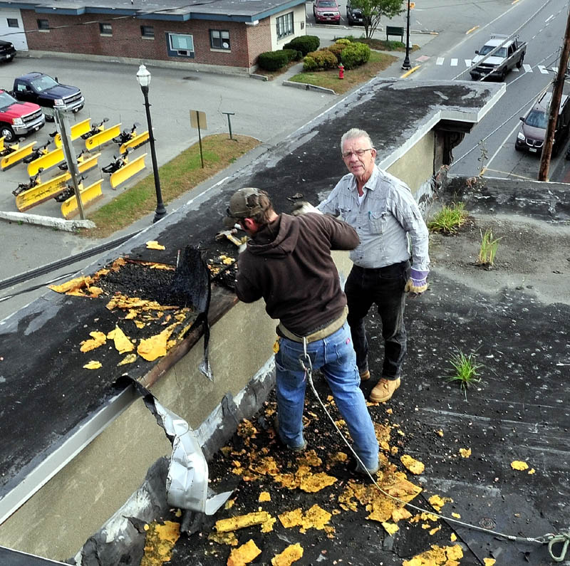 READY TO DROP: Tom McCarthy, right, owner of McCarthy Enterprises, oversees employee Lance Dionne on top of the Sweet Memories of Maine building in Skowhegan that will be torn down along with two other buildings.