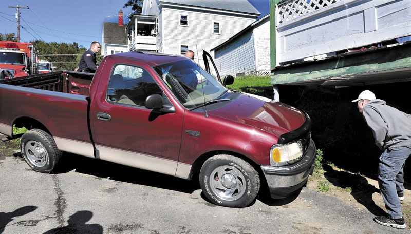 RUNAWAY TRUCK: Eric Olsen gets out of his truck while attempting to dislodge it from a support pole at an apartment building after the unoccupied vehicle rolled down Veterans Court in Waterville and ran into the building Thursday. Olsen said he needed a large jack to separate the truck. “I looked out of my house and my truck was gone,” Olsen said. No one was injured.