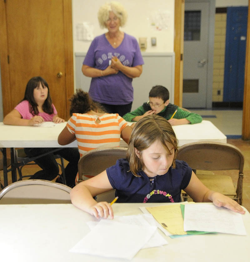 Lucy Pruett works on her homework during The 21st Century Afterschool Enrichment program on Tuesday afternoon at the Buker Center in Augusta. Barbara Helen Baker talks to children at another table in the background.