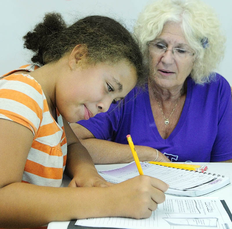 Akacia Anderson, left, gets some help on her homework from Barbara Helen Baker during The 21st Century Afterschool Enrichment program on Tuesday afternoon at the Buker Center in Augusta.