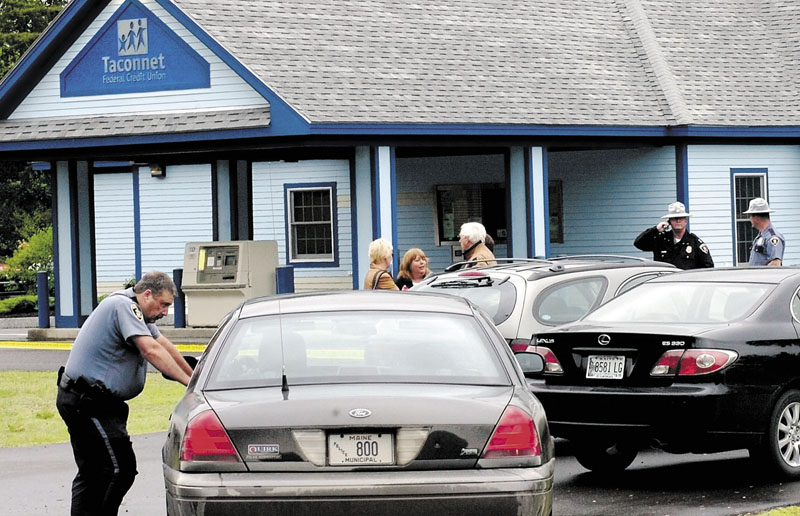 ROBBED: Skowhegan Deputy Chief Rick Bonneau, left, and other police officers and civilians gather outside the Taconnet Federal Credit Union in Skowhegan after an armed robbery in June 2009. Two local men were arrested last week and now face federal charges in the robbery.