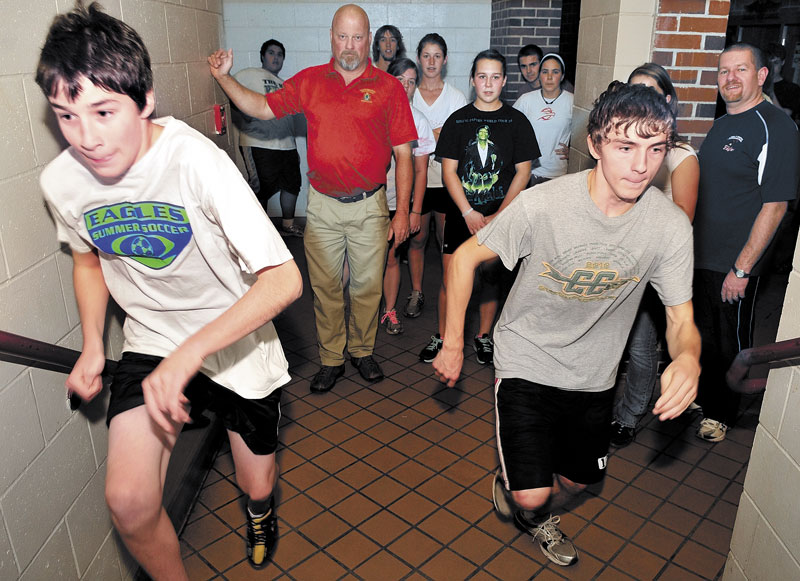 BACK TO WORK: Messalonskee High School indoor track coach Scott Wilson watches as sprinters William Couture, left, and Kyle Howard run up a flight of stairs during the first day of practice on Monday at Messalonskee High School.