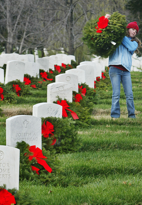 A volunteer helps place Christmas wreaths on the graves at Arlington National Cemetery in this 2004 photo.