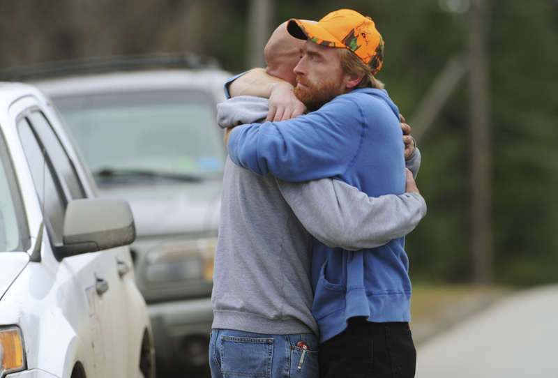 TWO FATALITIES: Jim Curtis, left, brother to Michael Curtis, is comforted by a friend in front of the Piscataquis Valley fairground in Dover-Foxcroft on Tuesday. Michael Curtis was shot and killed by a state trooper after walking into a nursing home and fatally shooting a maintenance worker.