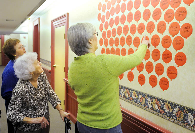 A DECADE LATER: Brenda Gross, right, helps her mother, Pauline Crocker, center, identify residents of the Inn at City Hall with Augusta elderly apartment complex administrator Lynda Pratt on Thursday, when they celebrated the 10th anniversary of the residence.