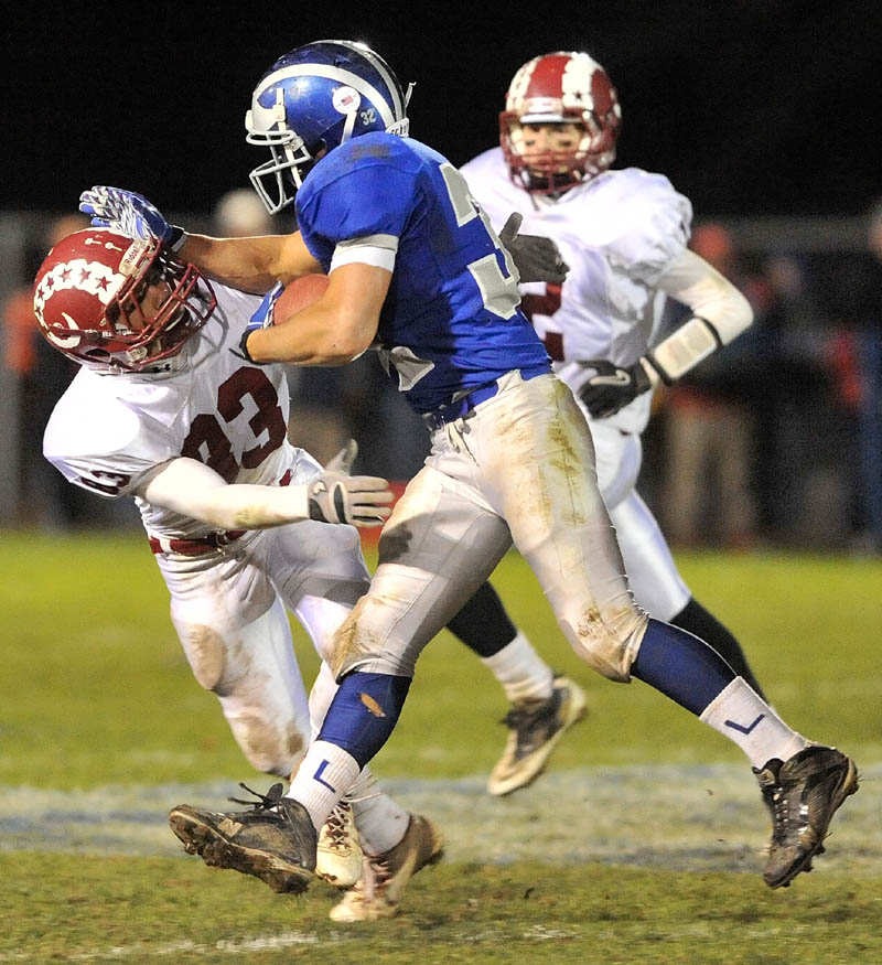 LOOK OUT: Lawrence High School running back Shaun Carroll, right, stiff arms Bangor High School defender Nick Sherwood in the second quarter of the Bulldogs’ 40-14 win in the Pine Tree Conference Class A title game Friday in Fairfield.