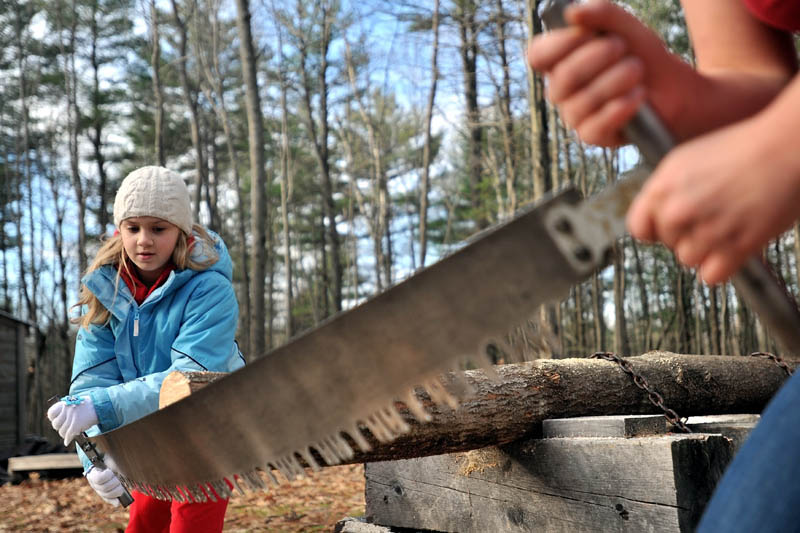 LEARNING NEW SKILLS: Emma Parrish, 9, of Oakland, handles a cross-cut saw with the help of Colby College sophomore Liz Schell as part of the Adventure Girls Series sponsored by Hardy Girls Healthy Women on Saturday afternoon in Waterville.