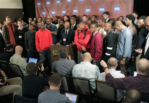 Surrounded by NBA players, Players Association president Derek Fisher, center, speaks during a news conference after a meeting of the players' union Monday in New York. The NBA players rejected the league's latest offer and have begun the process to disband the union.