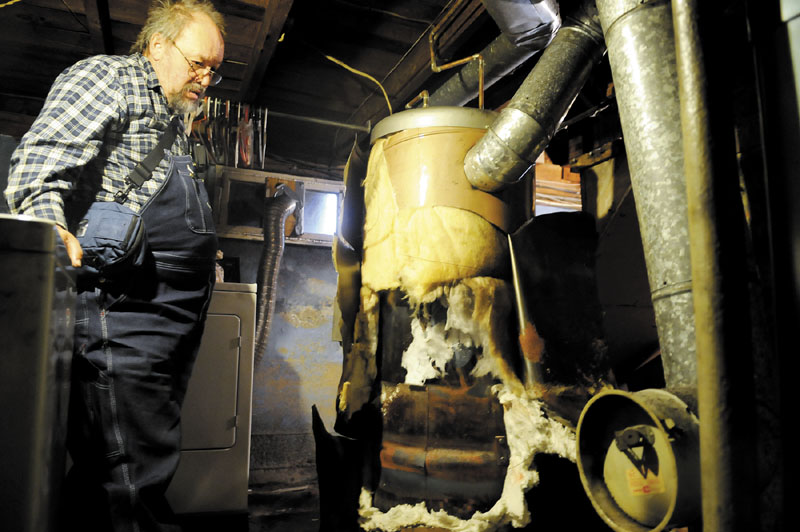 HEATING WOES: Craig Johnson surveys the hot water heater that was condemned last month in the basement of his Augusta home. Johnson — who has cancer — and his wife, Donna, went without heat and hot water for about a month before finding a solution this past week: They purchased a new hot water heater with their own money and a second heating technician fixed the oil tank leak, enabling the furnace to operate safely. “We had two angels come and help us,” Donna said, referring to the technicians. “We’re all set now.”