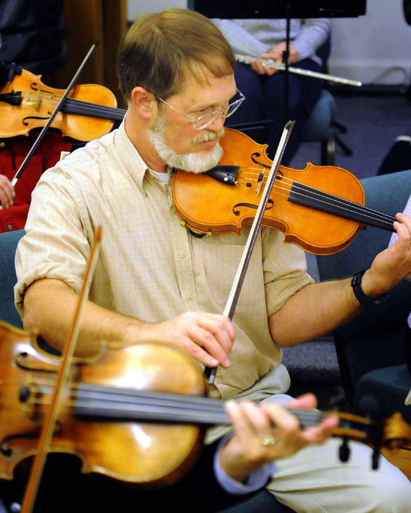 Nate Saunders rehearses Wednesday, with the violin he made. during a session with the Augusta Symphony Orchestra in Manchester.
