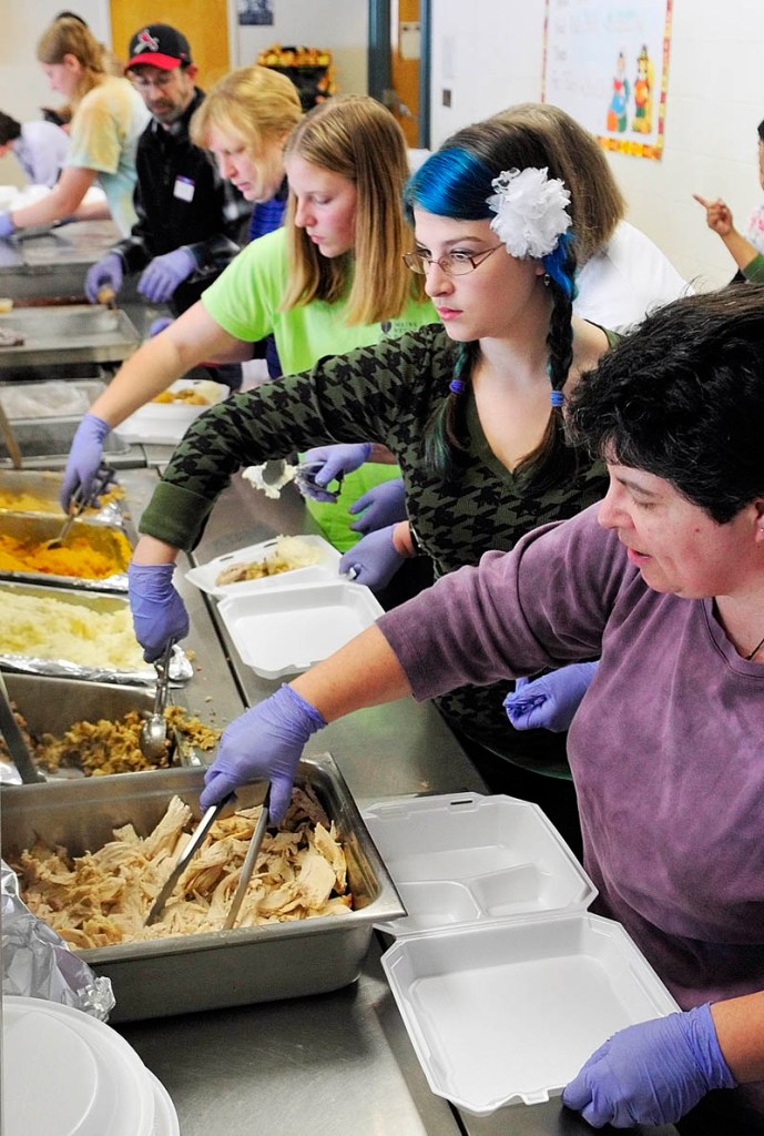 LONG LINE: A line of volunteers scoop up turkey, dressing, potatoes, squash and turnip into foam boxes on Thursday morning at Gardiner Area High School.