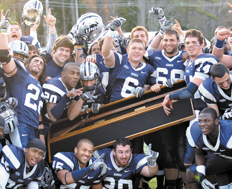 New Hampshire players hold up the Bryce-Cowell Musket after they defeated Maine 30-27 Saturday at Cowell Stadium in Durham, N.H.,