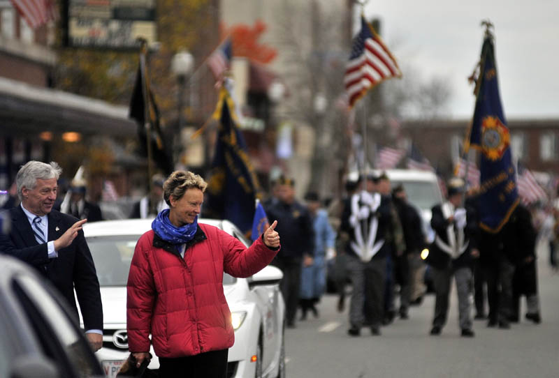 Staff photo by Michael G. Seamans Rep. Mike Michaud, left, and mayor-elect Karen Heck, wave to people on Main Street in Waterville during the Veteran's Day parade.