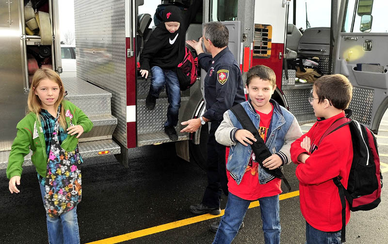 NICE RIDE; Skowhegan firefighter Rick Caldwell helps Bloomfield Academy students from left, Olivia Dunbar, Jeremiah Emery, Clay Porter and Damion Scanlin exit a firetruck after riding to school in the truck on Tuesday. Children in the school district wrote a fire safety checklist as part of Fire Prevention week, according to Caldwell. The kids names were picked in a raffle for the unique ride to school.