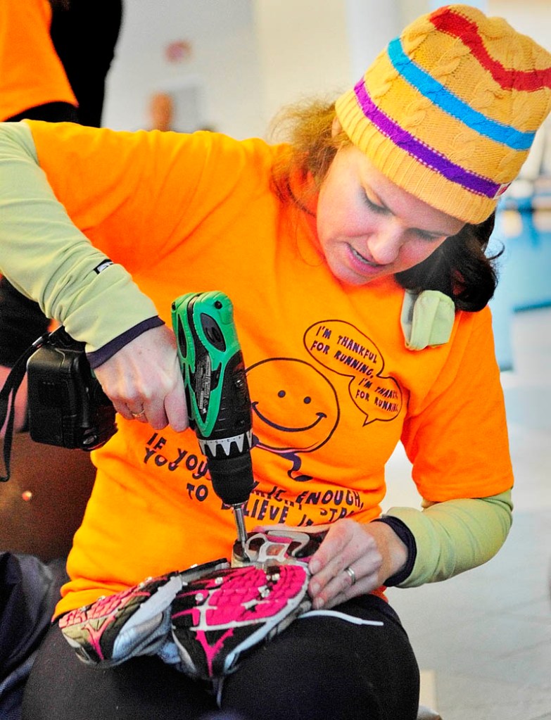 Amy Lawson drives 3/8 inch sheet metal screws into a teammate's running shoes on Thursday morning before the Gasping Gobbler 5K Road Race to Benefit Cony High School Athletics in Augusta. The screws are short enough that they don't go through the shoes and the heads give traction like studded snow tires on the icy roads.