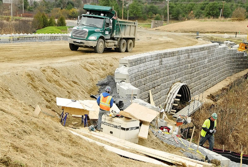 A dump truck drives along the main entrance road and over bridge on Stone Brook on Monday afternoon as construction work continues at the site of the new MaineGeneral hospital in Augusta.