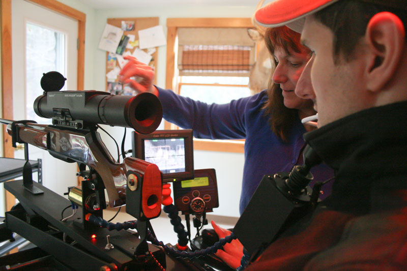 Christine Saban, left, helps her son, Jeff Molloy, attach an adaptive shooting device to his wheelchair Sunday at their Palermo home. Molloy and his friend, machinist Ray Kimball, designed and built the device, called the Equalizer Shooting System. On Nov. 12 in Albion, Molloy used the system to bag a 118-pound four-point buck.