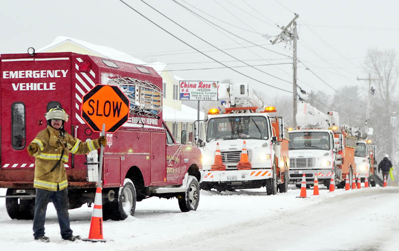 THIS WAY: Richmond firefighter Pete Lilly directs traffic around Central Maine Power Co. workers who were replacing a broken pole Wednesday morning on Main Street in Richmond. The top of the pole snapped after a fire earlier in the morning.