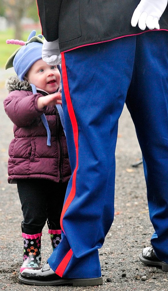 Lily Snyder toddles over to greet her father Marine Staff Sgt. Brice R. Snyder during Veterans Day ceremony in the Hallowell city cemetery Friday morning. Snyder was a guest speaker at the event that featured singing of patriotic songs and placing a wreath.