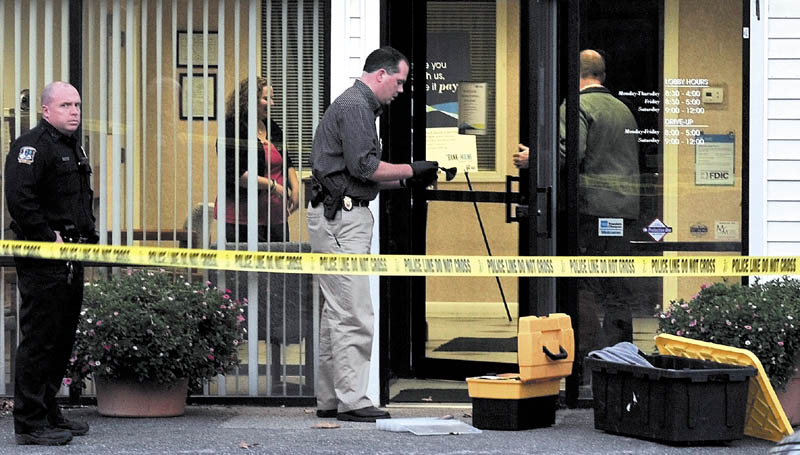 ANOTHER ROBBERY: Waterville police Detective David Caron dusts the door of the Waterville Savings Bank of Maine for fingerprints shortly after a reported armed robbery on Wednesday at the Upper Main Street bank. Officer Dennis Picard is at left and more police and employees were inside. It is the second bank robbery in 48- hours in Waterville.